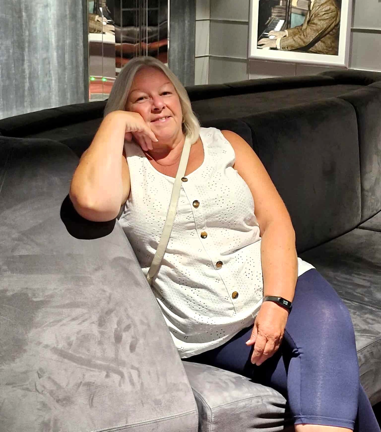 Mandy sits on a sofa smiling at the camera.