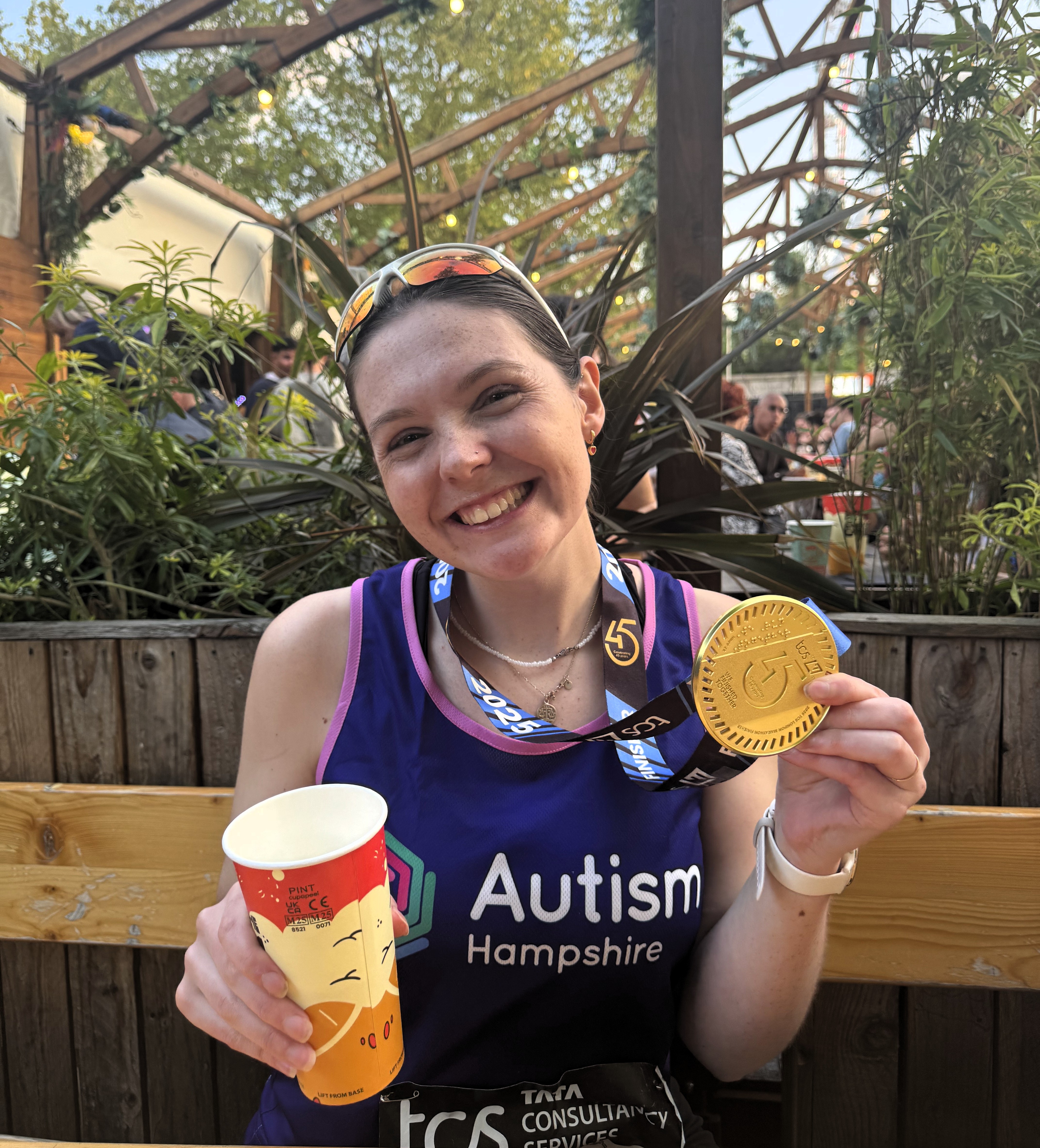 Poppy smiles at the camera with her marathon medal and Autism Hampshire running vest.
