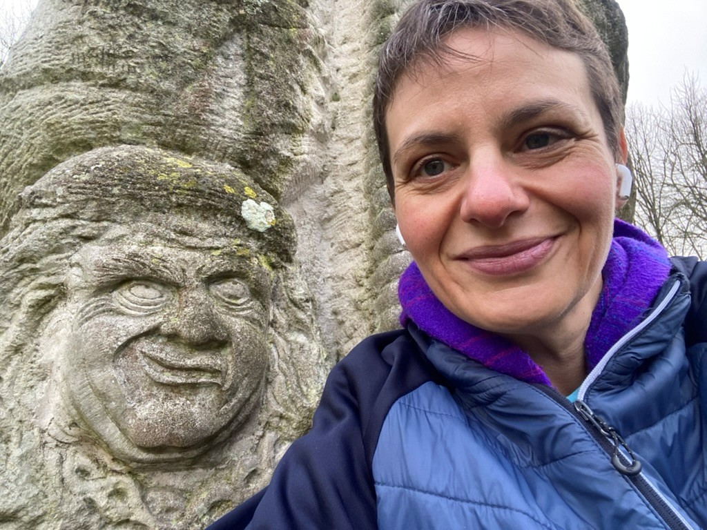 Sarah Clark smiles at the camera with a carved stone figure in the background.