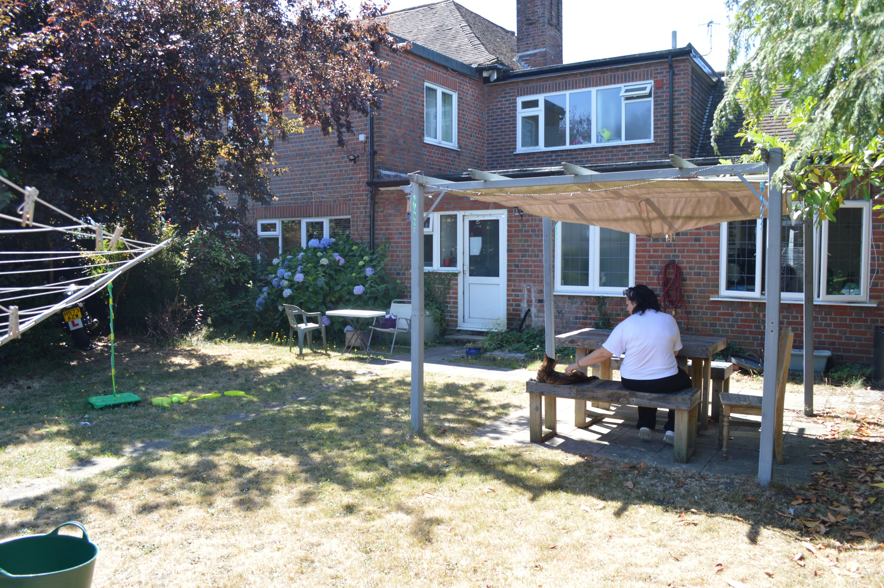 Kirstie sits in the garden with the house in the background.
