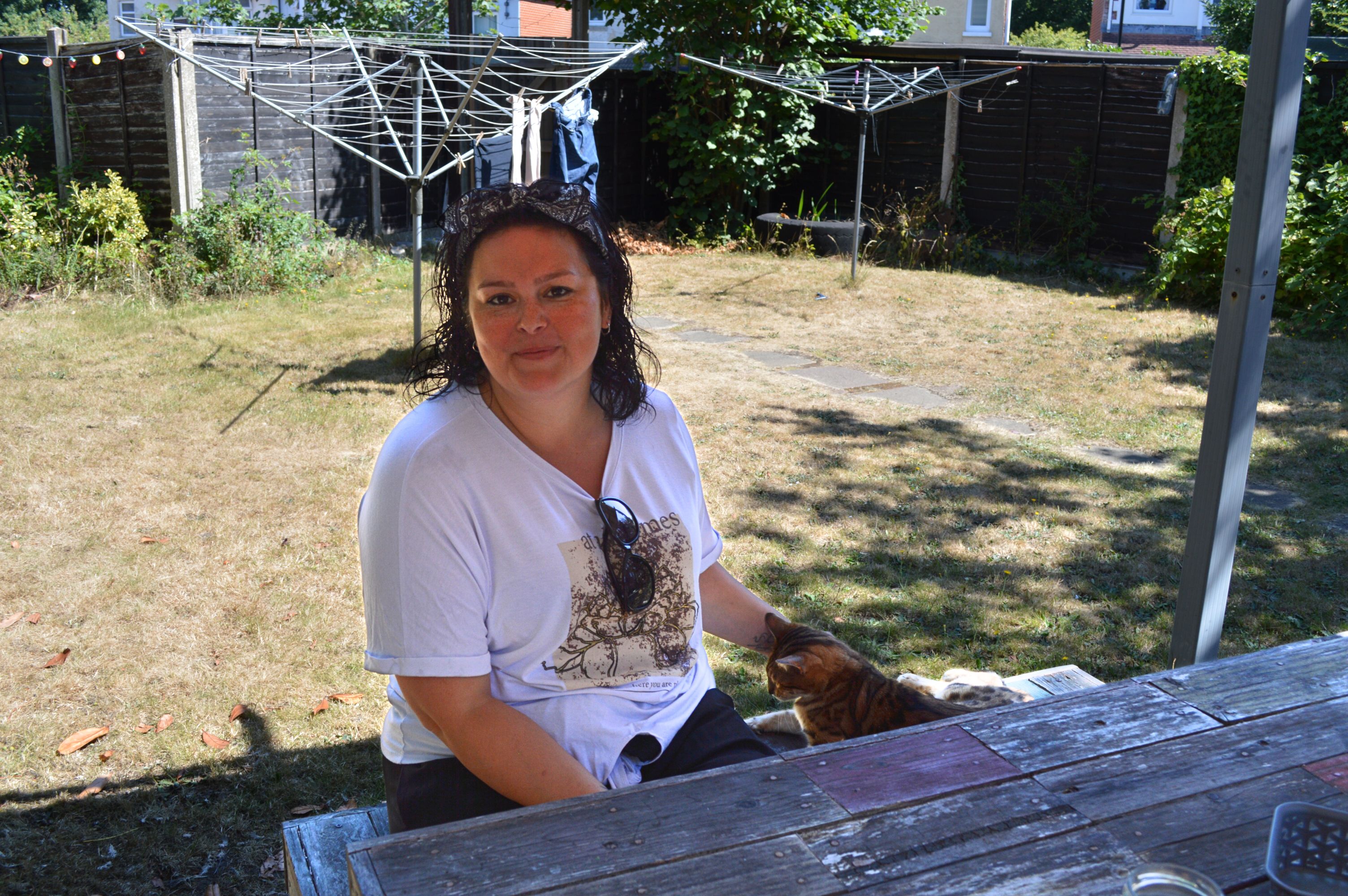 Kirstie Burgess smiles at the camera sitting on a bench in the garden.