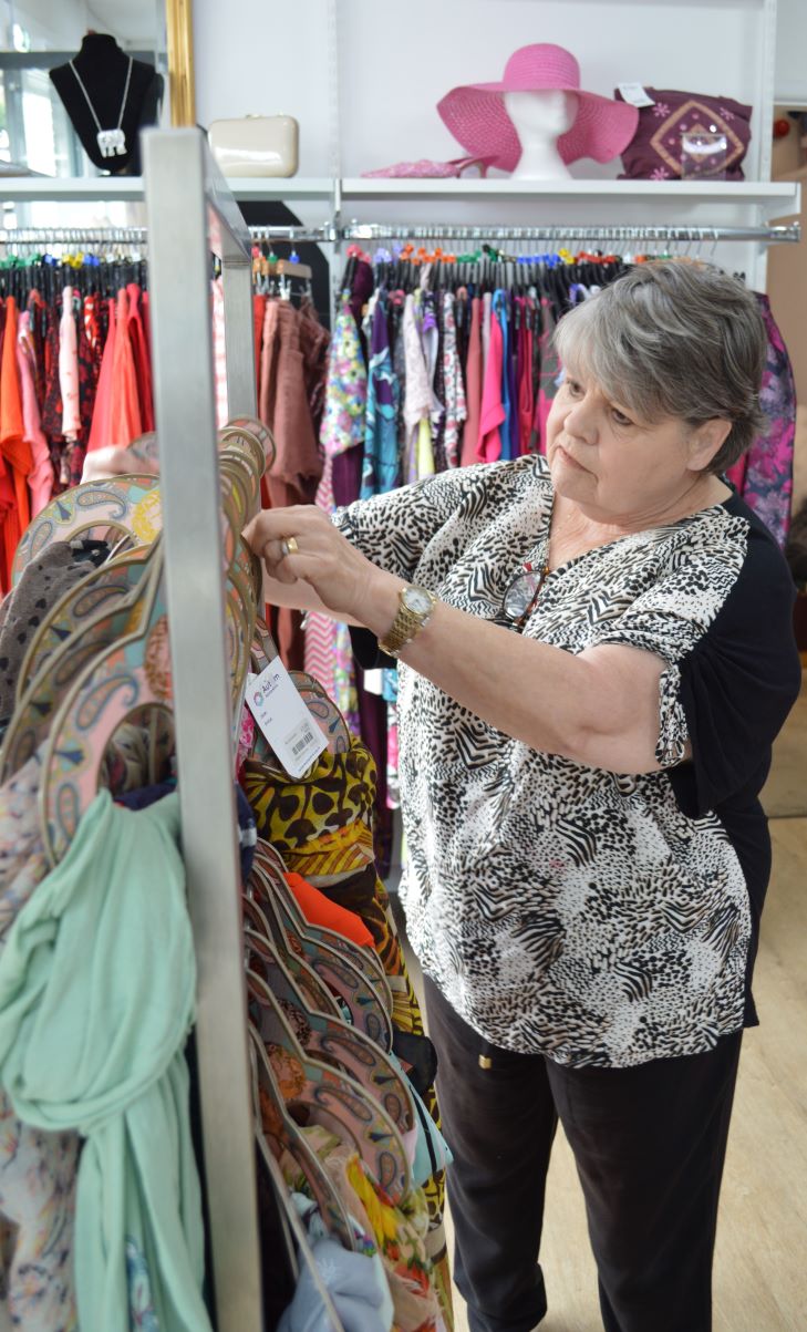 Linda Slatcher stands in the shop tidying up a scarf display