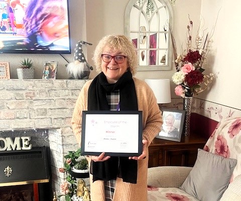 Maxine smiling to the camera receiving her award certificate